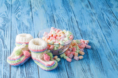 Infant booties with sweets on blue wooden backgroundの写真素材