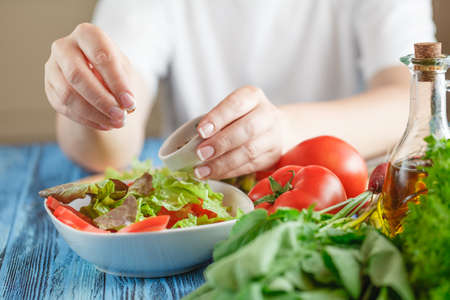 Woman's hands adding spices for a vegetable saladの写真素材