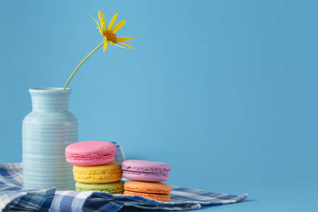 Pile of macaroons and yellow flower with copy space on light backgroundの写真素材