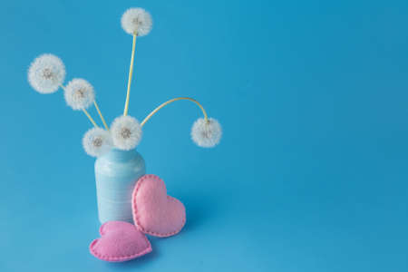 Light dandelions and heart on blue background with copy spaceの写真素材