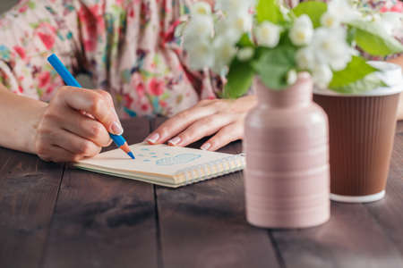 Woman drawing on notebook paper on wooden tableの写真素材