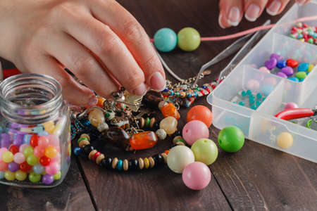 Close up of woman hand threading beads on drawstring to make artistic bead necklace or bracelet
