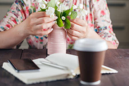 Coffee to go with Woman hold white flowers on the rustic background.の写真素材