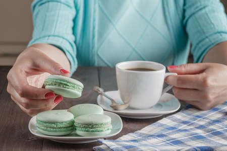Female hands holding colorful french macaroons
