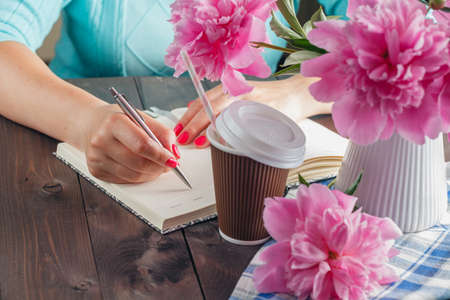 Woman write in notebook, flowers on table, Vacation work