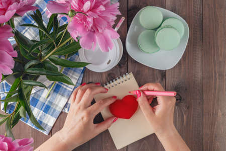 Writing love message with red heart shape and peony flowers