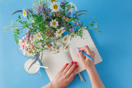 Woman write in notebook. Summer bright scene with wildflowersの写真素材