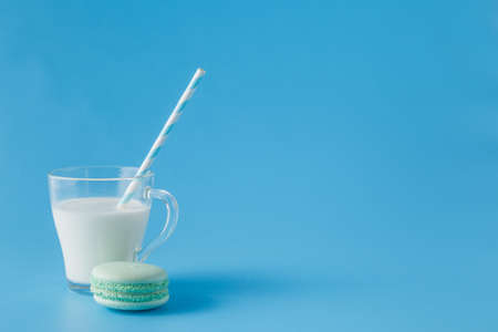 Glass of milk with french macaroon on blue background with copy spaceの写真素材