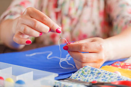 Thread insert into a needle in woman hands on tableの写真素材
