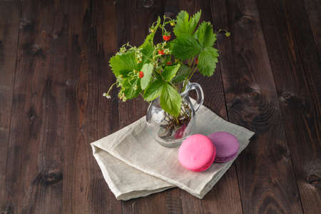 Colorful French Dessert Macaroons, Flowers, Berries on Rustic Wooden Background.の写真素材