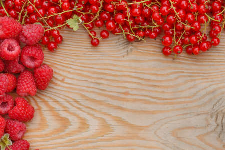 Fresh ripe raspberries and currand on wooden table background with copy space