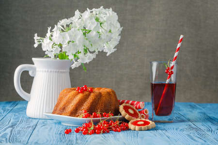 Fresh currant cocktail on the wooden table with ring cakeの写真素材