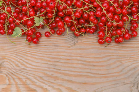 Berries of a red currant and laptop on the brown wooden texture
