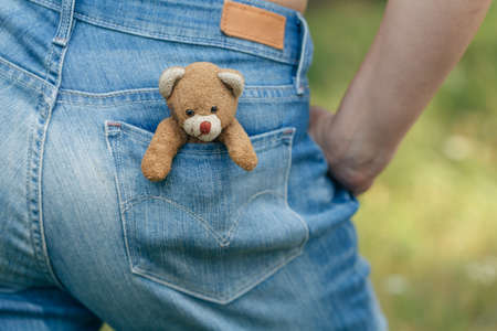 Handmade toy Teddy bear in the pocket blue jeans. Teddy Bear looks out of pocketの写真素材