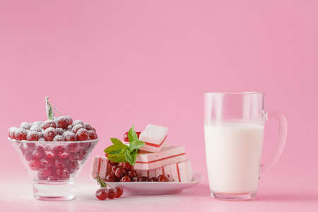 Glass of milk and wild cherry with sugar powder on pink backgroundの写真素材