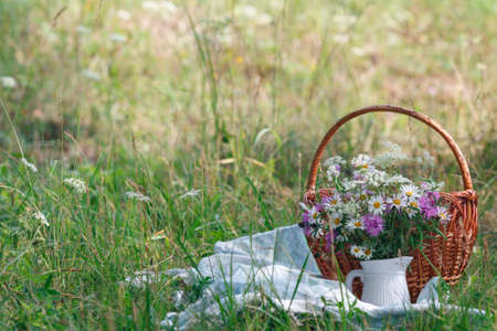 picnic in a meadow scene with basket and flowersの写真素材