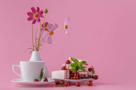 Little delicate elegant bouquet of flowers, buttercups and  teacup on pink table, morning breakfastの写真素材