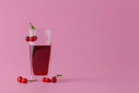 Glass of fresh juice with cherries on pinkの写真素材