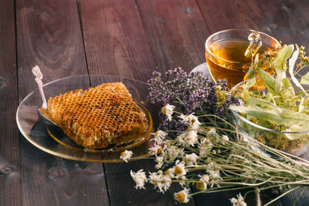 Golden honeycomb with honey and tea linden flowers on wooden backgroundの写真素材