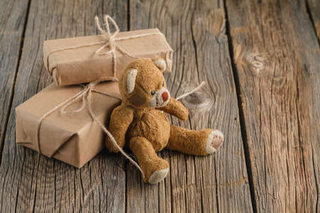 Valentine's day homemade gifts in craft paper with hearts tags, Toy bear on wooden rustic tableの写真素材