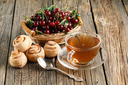 homemade cheesecake on an old wooden table with fresh cherries, a cup of teaの写真素材