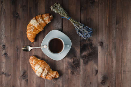 Coffee and lavender on wooden table with croissantの写真素材