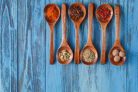 Colorful Spices and herbs on rustic spoons over blue wooden backgroundの写真素材