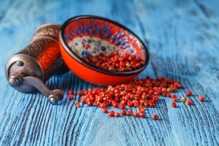 Bowl of pink pepper on blue tableの写真素材