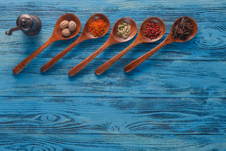 Colorful spices on wooden spoons placed on blue grunge wooden table.の写真素材