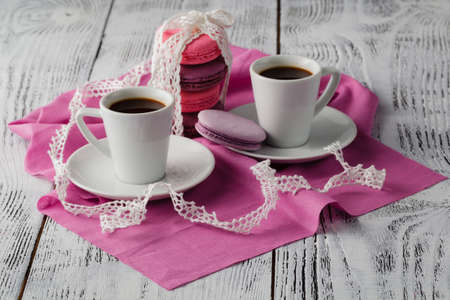 Two cup of espresso coffee with macaroons on pink backgroundの写真素材