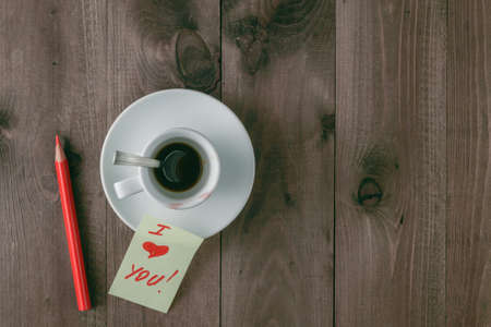 Empty cup of coffee with traces of lipstick on the table with sticker i love youの写真素材