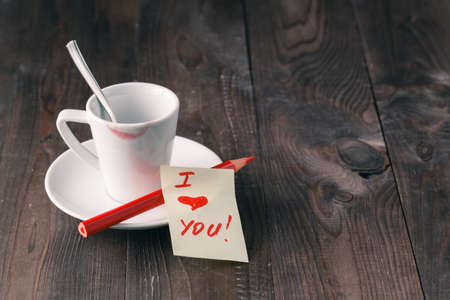 Cup of coffee with lipstick mark and note 'i love you' on table close upの写真素材