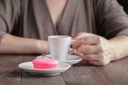 One macaroon and espresso coffee in womans handsの写真素材