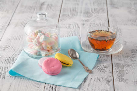 Sweet and colourful french macaroons with tea cup on white tableの写真素材