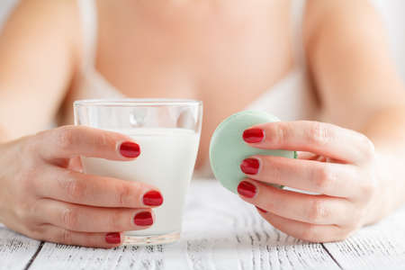 Glass of milk with Tasty macaroon in hands
