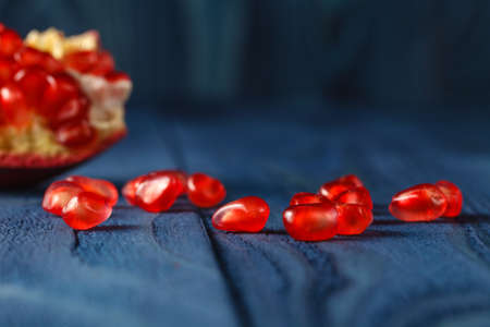 Ripe pomegranate slice and red garnet fruit seeds on table. Selective focusの写真素材