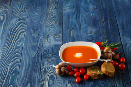 White plate of fresh cold tomato gazpacho soup on old wooden background.の写真素材