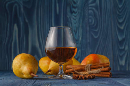 Glass of cognac and ripe juicy pears conference on a dark wooden tableの写真素材