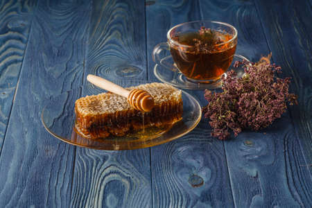 wildflower honey on wooden table next to honeycomb with honey dipperの写真素材