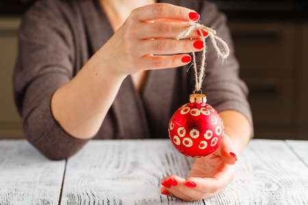 Girl holding Christmas ball in fingers. Beautiful manicure on a background of the red ball.の写真素材