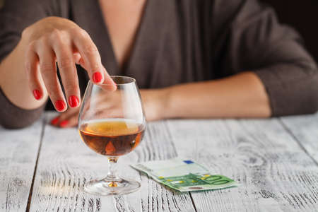 A woman's hand is touching a glass of cognacの写真素材