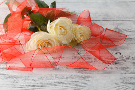 Bouquet of white roses decorated with ribbon on white wooden backgroundの写真素材