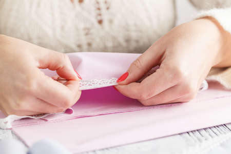 Woman hands sewing lace on white tableの写真素材