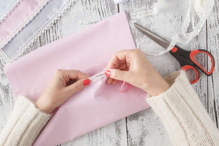 Women's hands hold the laces on the background of colorful clothesの写真素材