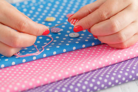 A woman is doing needlework with other embroidery equipment on a table