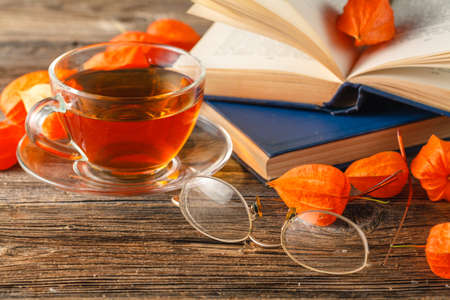 Hot coffee, vintage book, glasses and autumn leaves on wood background - relax or retirement conceptの写真素材