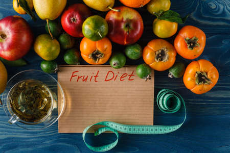 Fruits, vegetables and in measure tape in diet on wooden backgroundの写真素材