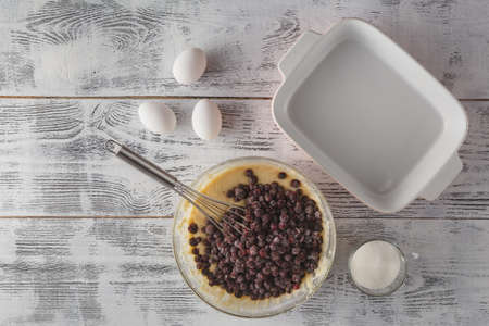 Whole-wheat flour in white bowl, milk, eggs on a light wooden background. Baking rustic backgroundの写真素材