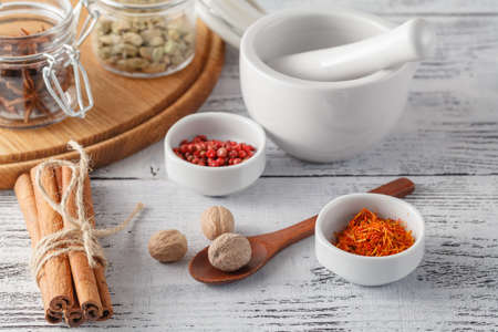 Mortar and pestle with pepper and spices on wooden tableの写真素材