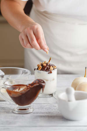 Close up on delicious peeled pear with melted chocolate on top for concept about decadent dessertsの写真素材